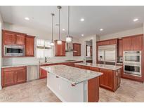 A spacious kitchen featuring rich wood cabinetry, stainless steel appliances, and two granite-topped islands for ample workspace at 4724 S Anitole Way, Mesa, AZ 85212
