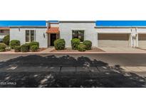 Charming townhome featuring white stucco, a red tile awning, a garage, and well-maintained landscaping at 5314 N Las Casitas Pl, Phoenix, AZ 85016