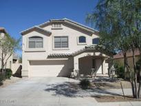 Beige two-story home featuring a two-car garage and covered front porch, landscaped with desert vegetation at 16696 W Culver St, Goodyear, AZ 85338