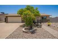 Charming single-story home featuring a xeriscaped front yard, mature tree, and a neutral color palette at 6802 S 47Th St, Phoenix, AZ 85042