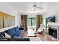 Bright living room featuring a plush blue sofa, fireplace, and natural light from large windows at 15095 N Thompson Peak Pkwy # 3032, Scottsdale, AZ 85260