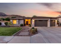 Charming home with a well-manicured front yard, desert landscaping, and a three-car garage, set against a mountainous backdrop at 4618 W Pokeberry Ln, Phoenix, AZ 85083