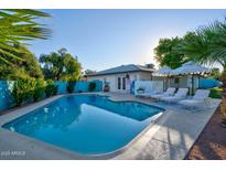 Inviting backyard pool area featuring a refreshing pool, lounge chairs, and stylish umbrellas under a clear blue sky at 8102 E Cambridge Ave, Scottsdale, AZ 85257