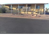Tan mobile home featuring a porch and well-maintained landscaping, enhancing curb appeal at 8600 E Broadway Rd # 91, Mesa, AZ 85208