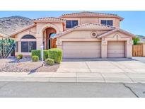 Charming home featuring a tile roof, arched entry, desert landscaping, and a three-car garage at 22019 N 59Th Dr, Glendale, AZ 85310