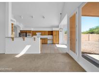 Open-concept kitchen featuring wood cabinetry and a breakfast bar leading to dining and living area at 22019 N 59Th Dr, Glendale, AZ 85310