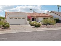 Charming single-story home featuring a terra cotta roof, desert landscaping, and an attached two-car garage at 6719 W Kerry Ln, Glendale, AZ 85308