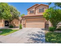 Two-story tan home featuring a two-car garage, well-maintained lawn and mature landscaping at 931 S Racine Ln, Gilbert, AZ 85296