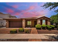 Charming single-story brick home with a tiled roof, manicured landscaping, and a two-car garage at 10618 E Kinetic Dr, Mesa, AZ 85212