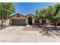 Charming single-story home features a well-manicured front yard, mature trees, and a two-car garage at 12325 W Berridge Ln, Litchfield Park, AZ 85340