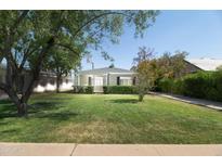 Charming single-story home with lush green lawn, mature trees, and covered front porch at 1609 W Lewis Ave, Phoenix, AZ 85007