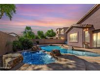 Backyard pool with rock features and desert landscaping offers a luxurious outdoor retreat at sunset at 4662 S Calico Rd, Gilbert, AZ 85297