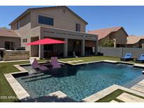 Resort-style backyard featuring pool with baja step, covered patio, and artificial grass at 10430 W Los Gatos Dr, Peoria, AZ 85383