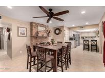 Spacious dining area with a view of the kitchen, a brick fireplace, and tile flooring at 10820 N 45Th Dr, Glendale, AZ 85304