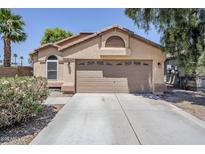 Tan single-story home featuring a two-car garage and low maintenance desert landscaping at 1616 N 125Th Ln, Avondale, AZ 85392