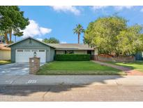 Charming single-Gathering home featuring a lush lawn, mature trees, and a brick-accented facade at 216 E Harmont Dr, Phoenix, AZ 85020