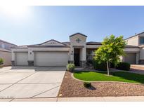 Attractive single-Gathering home featuring a three-car garage and manicured front yard with green grass and decorative rock at 3026 N 305Th Dr, Buckeye, AZ 85396