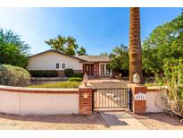 Charming home featuring a well-manicured front yard with a brick and stucco fence, gate, and mature landscaping at 5744 E Oak St, Scottsdale, AZ 85257