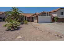 Charming single-story home with desert landscaping and a spacious two-car garage and a red tile roof at 5911 E Evergreen St, Mesa, AZ 85205