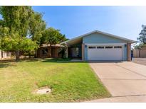 Charming single-story home with a well-maintained lawn, mature trees, and a two car garage at 2161 E Harmony Cir, Mesa, AZ 85204