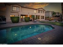 Tranquil backyard with a shimmering pool, covered patio, and ample green space for outdoor enjoyment at 7156 S Forest Ave, Gilbert, AZ 85298