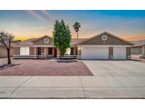 Charming single-story home with a three car garage and well-kept yard at sunset at 10943 W Alice Ave, Peoria, AZ 85345