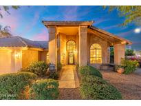 Inviting front entrance with stone pathway, lush landscaping, large arched windows, and decorative iron door detail at 19275 N 88Th Way, Scottsdale, AZ 85255