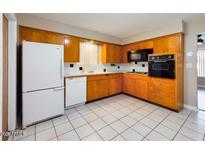 Cozy kitchen featuring light wood cabinets, black appliances and white tiled floors and counters at 5414 E Albany St, Mesa, AZ 85205
