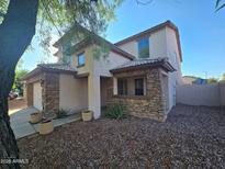 Charming two-story home featuring a stone facade, inviting entrance, and well-maintained desert landscaping at 25748 W Siesta Way, Buckeye, AZ 85326