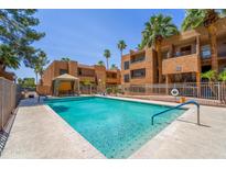 Community pool with clear blue water surrounded by lush landscaping and a relaxing cabana at 2625 E Indian School Rd # 206, Phoenix, AZ 85016