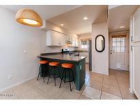 Well-lit kitchen featuring tiled floors, breakfast bar with seating, and white cabinetry at 860 N Mcqueen Rd # 1151, Chandler, AZ 85225