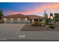 Home with a three-car garage and desert landscaping at dusk with street view at 10152 E Aster Dr, Scottsdale, AZ 85260