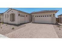 Two-car garage with desert landscaping and a brick driveway leading up to the house at 16981 W Cameron Dr, Surprise, AZ 85388