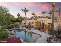 An inviting lagoon-style pool surrounded by lush landscaping, lounge chairs, and a resort-like atmosphere at 7640 E Poinsettia Dr, Scottsdale, AZ 85260