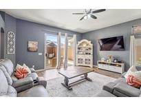 Inviting living room with slider to patio, ceiling fan and view of backyard at 11550 W Mule Deer Ct, Surprise, AZ 85378