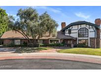 Charming two-story brick home featuring a manicured front lawn, mature tree, and brick driveway at 211 W Kaler Dr, Phoenix, AZ 85021