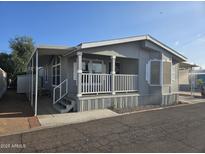 Charming home exterior with covered porch, white railings, and well-maintained landscaping under a clear blue sky at 2121 N Center St # 131, Mesa, AZ 85201