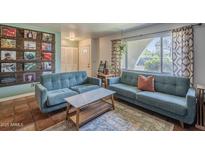 Inviting living room featuring blue sofas, unique coffee table, and decoratively adorned walls with vintage records at 2818 E Clarendon Ave, Phoenix, AZ 85016