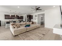 Bright open-concept living room featuring a large sectional couch, modern ceiling fan, and seamless flow to kitchen at 36922 N Camarillo Dr, San Tan Valley, AZ 85140