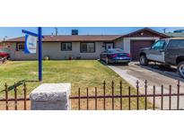 Modest single-story home with a brown roof, a blue car parked on the driveway, and a small fenced front yard at 6063 W Earll Dr, Phoenix, AZ 85033