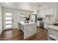 Bright kitchen with waterfall island, stainless appliances, white cabinets, and wood-look floors at 8022 E Columbus Ave, Scottsdale, AZ 85251