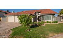 Charming home featuring a manicured lawn, mature tree, and a two-car garage at 11615 N 77Th Dr, Peoria, AZ 85345