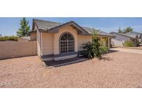 Single-story home featuring a gray tiled roof, neutral stucco, decorative window, and minimal desert landscaping at 1165 E Ivanhoe St, Chandler, AZ 85225