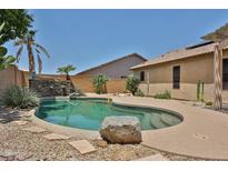 Refreshing backyard pool with lush desert landscaping and a stone waterfall feature for ultimate relaxation at 16126 N 159Th Dr, Surprise, AZ 85374