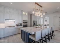 Modern kitchen boasts a large island with marble countertop, seating, and stylish lighting at 16425 S 34Th St, Phoenix, AZ 85048