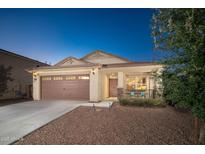 Charming home featuring a brown two-car garage and inviting front porch with stone accents at 18344 W Getty Dr, Goodyear, AZ 85338