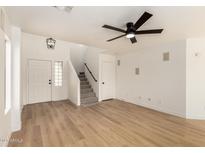 Bright living room features wood floors, a ceiling fan, and staircase to the second floor at 2112 S 160Th Dr, Goodyear, AZ 85338