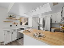 Bright kitchen featuring butcher block island, stainless steel appliances, and modern track lighting at 2455 E Broadway Rd # 122, Mesa, AZ 85204