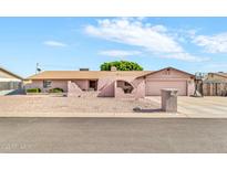Single-story home with arched entry, desert landscaping, and driveway with basketball hoop at 6055 E Hannibal St, Mesa, AZ 85205