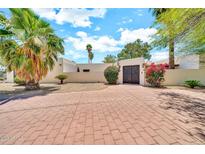 Charming home featuring a brick driveway, desert landscaping, and decorative metal gate for secure and stylish curb appeal at 6215 E Surrey Ave, Scottsdale, AZ 85254